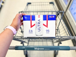 Hand touching case of Michelob Ultra beer while it's inside the shopping cart