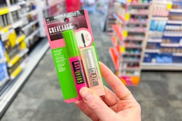 person holding maybelline mascara and lifter glaze lip gloss