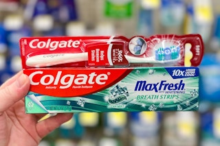 hand holding colgate toothpaste and toothbrush