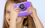 a kid taking a picture with a purple camera