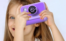 a kid taking a picture with a purple camera