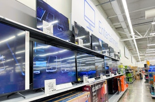 large screen tvs on display against back wall of walmart store with entertainment section sign above them