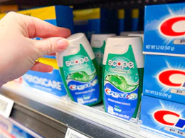 hand pulling a container of toothpaste off the Walmart shelf