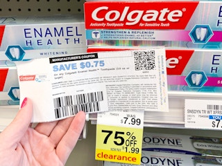 person holding a manufacturers coupon for colgate toothpaste in cvs