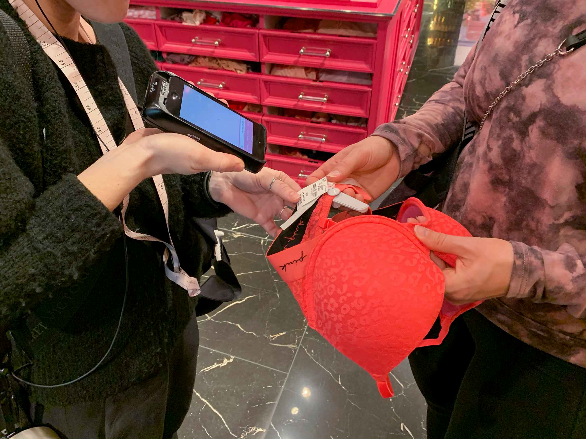An employee scanning a bra held by a customer.