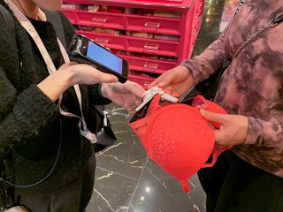 An employee scanning a bra held by a customer.