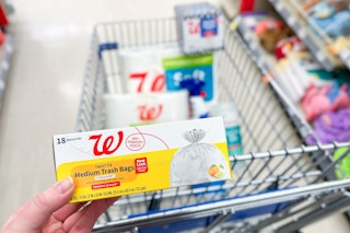hand hollding walgreens brand trash bags next to shopping cart