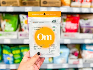 Om Mushroom Powder held up in front of similar products in Walmart store