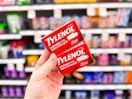 hand holding 2 boxes of extra strength tylenol in front of target shelves
