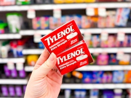 hand holding 2 boxes of extra strength tylenol in front of target shelves