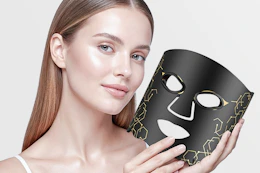 a woman holding a red light mask