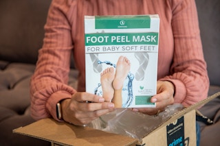 A woman holding up a foot peel mask set.
