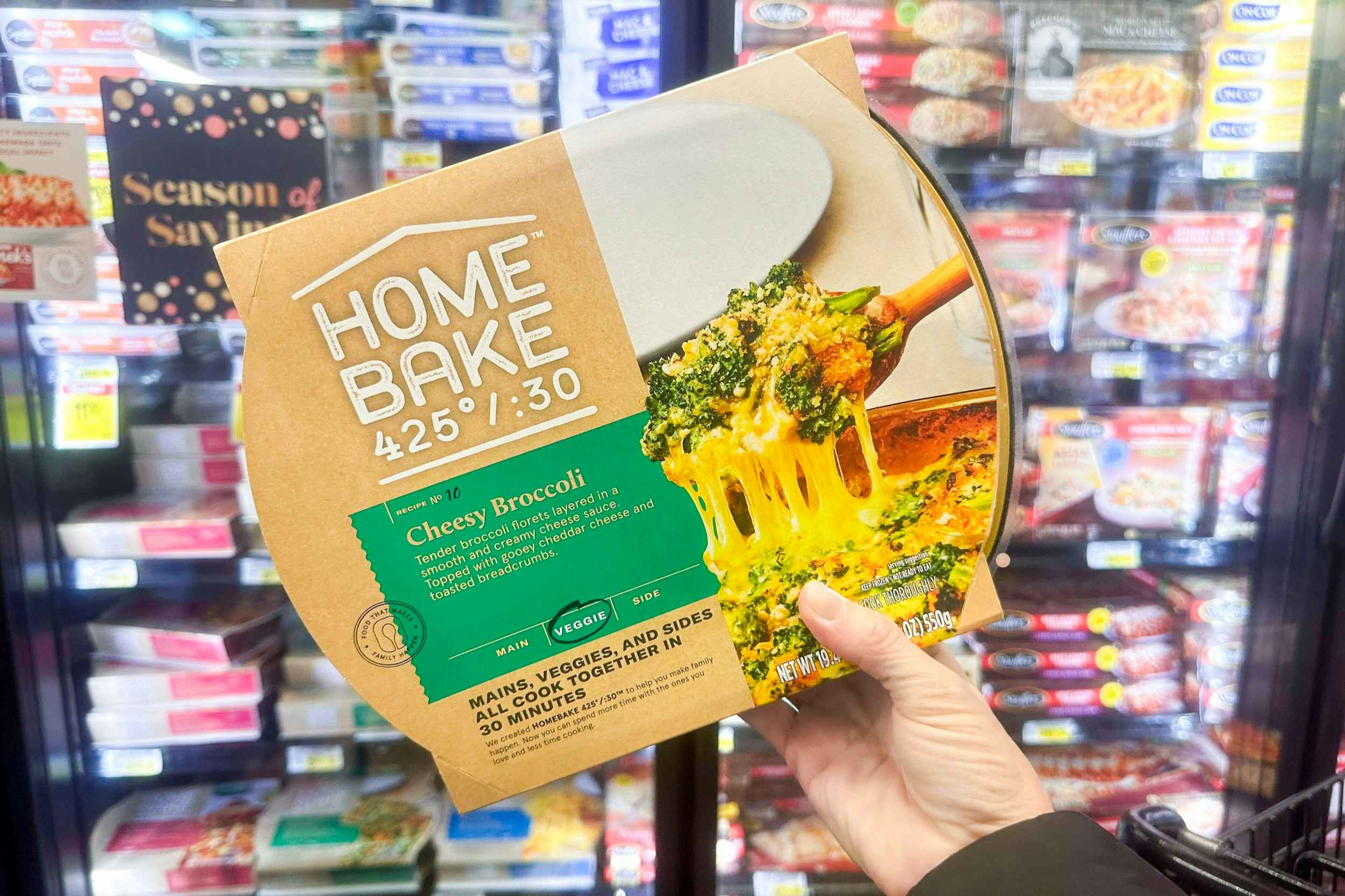 someone holding up a cheesy broccoli home bake meal in a store