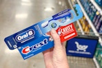 hand holding crest toothpaste oral b toothbrush