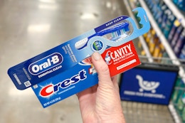 hand holding crest toothpaste oral b toothbrush