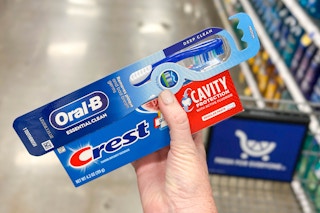 hand holding crest toothpaste oral b toothbrush