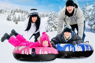 man and woman with two children on snow tubes