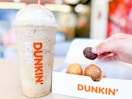 Person holding a dunkin donut munchkin with a drink
