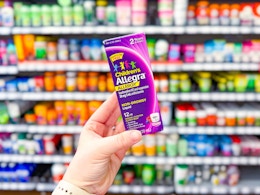 Lifestyle image of children's Allegra allergy medicine held up in medicine aisle at Walmart