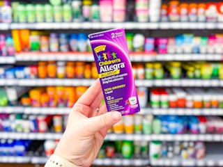 Lifestyle image of children's Allegra allergy medicine held up in medicine aisle at Walmart