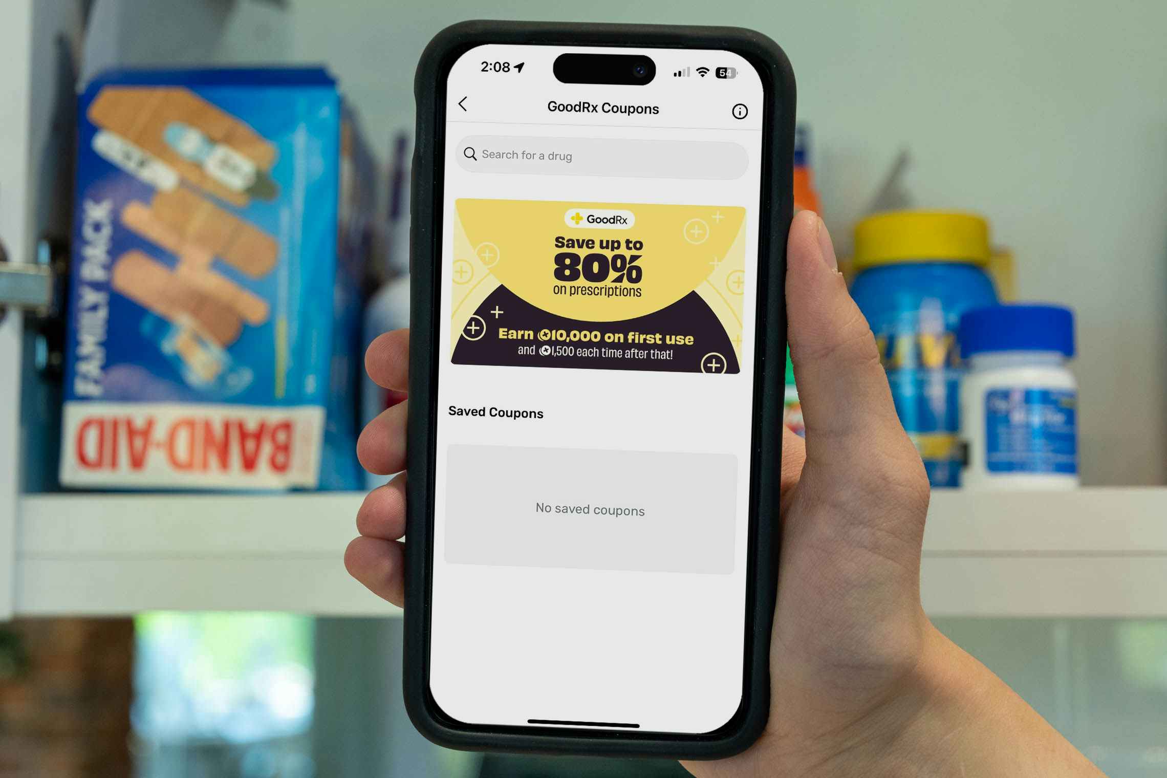 someone holding up their phone displaying the goodrx page of the fetch app in front of a medicine cabinet in the bathroom