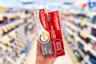 hand holding two colgate toothpastes in store aisle