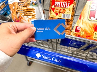 a person holding a sams club members card next to cart 