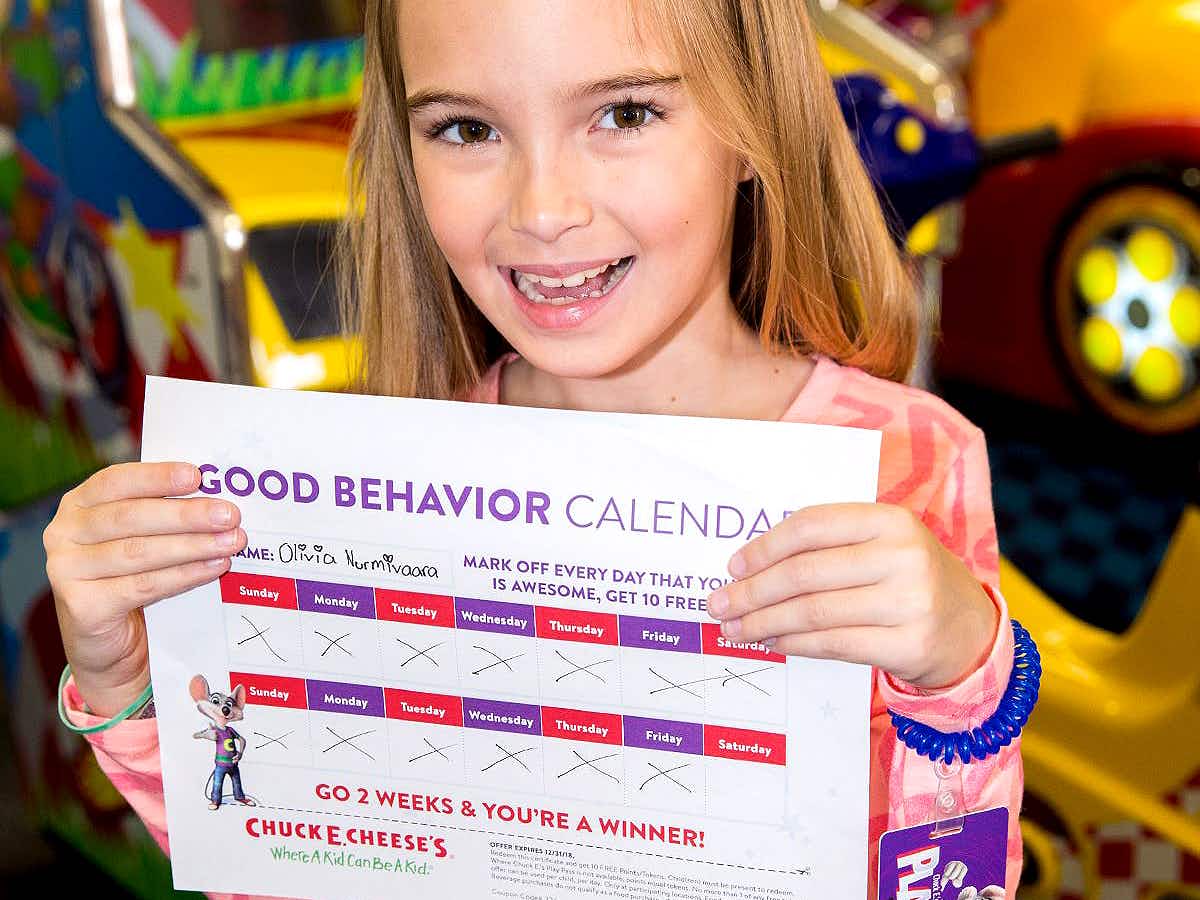 child holding a good behavior calendar in chuck e cheese