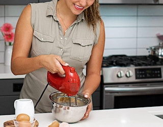 a woman using a hand mixer in a bowl