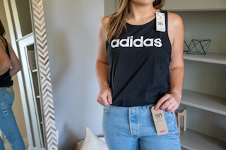 A woman trying on Levi's jeans and an adidas tank top.