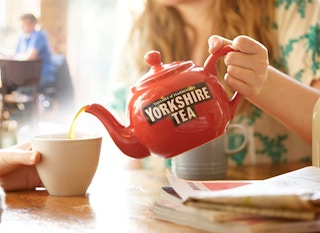 a person pouring tea from a tea pot