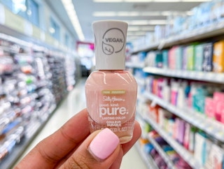 hand holding bottle of Sally Hansen Good.Kind.Pure. nail polish in aisle