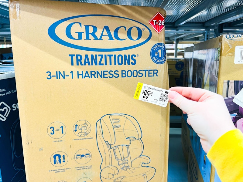 Hand holding clearance tag next to Graco Tranzitions Booster at walmart