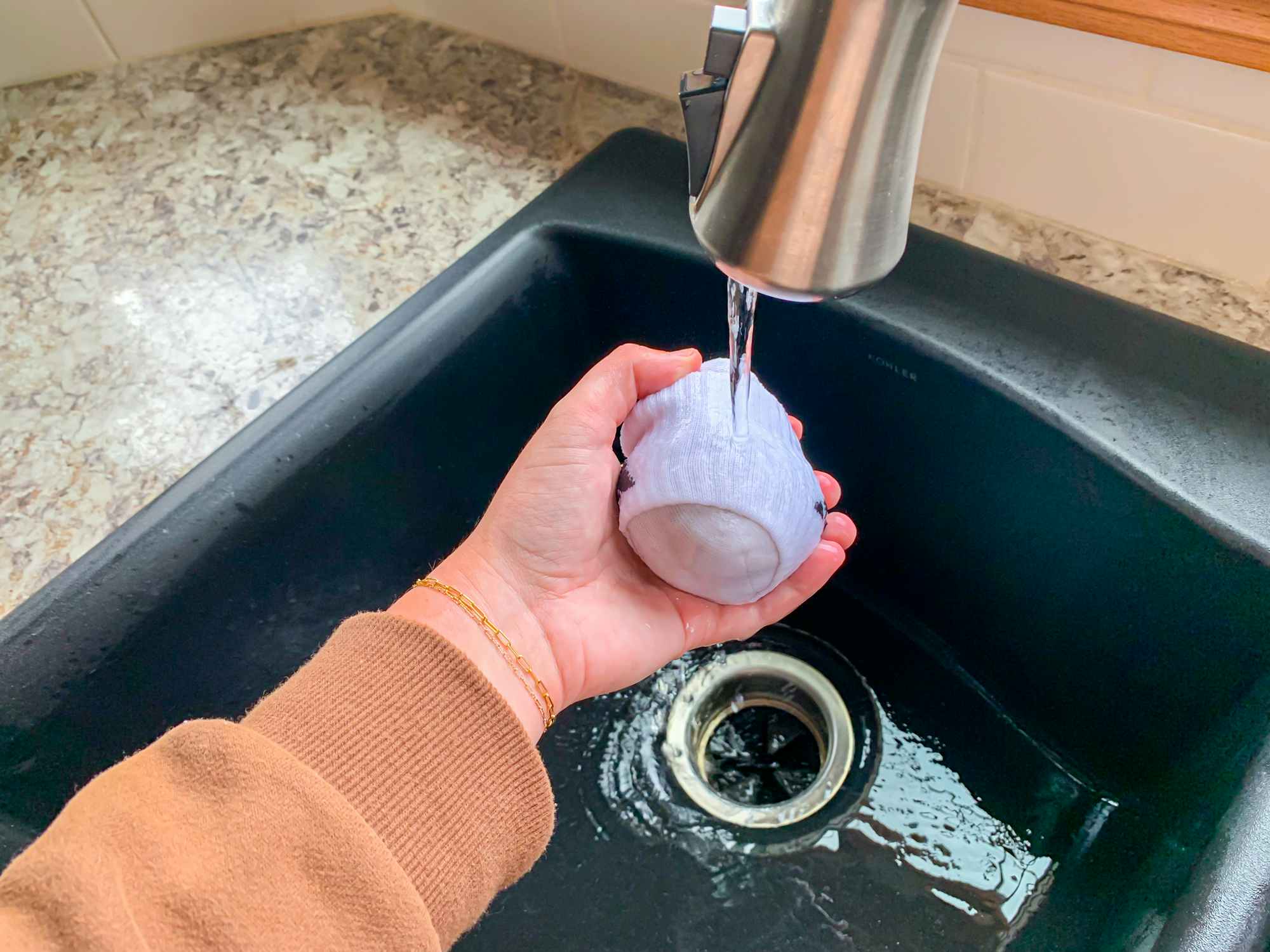 a person putting a sock ball under a water faucet