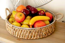 Lifestyle image of a DecMode Wicker Table Tray with fruit inside