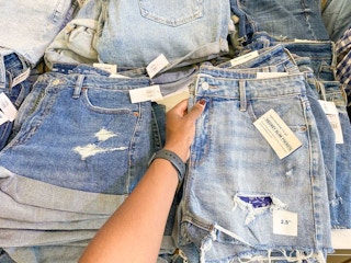 person holding jean shorts on shelf