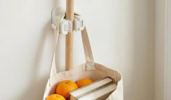 a broom and bag hanging on a broom holder on a wall