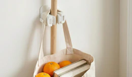 a broom and bag hanging on a broom holder on a wall