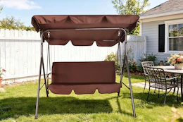 Lifestyle image of a brown 3-person patio swing outdoor in backyard setting