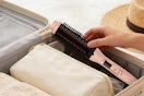 person putting thermal brush in to lugage