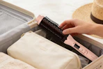 person putting thermal brush in to lugage