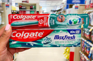 hand holding Colgate manual toothbrush and toothpaste in aisle