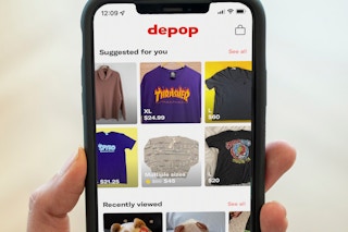 A hand holding up a cell phone displaying the Depop app.