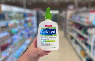 A person holding a bottle of Cetaphil lotion.