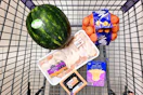 watermelon, chicken drumsticks, blueberries, mandarins, and sliced cheese in a cart