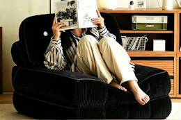 woman sitting on black folding sofa