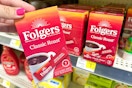 hand holding folgers instant coffee in front of a dollar general shelf