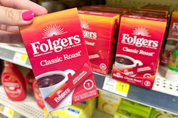 hand holding folgers instant coffee in front of a dollar general shelf