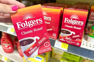 hand holding folgers instant coffee in front of a dollar general shelf