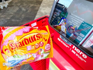 person holding a bag of starburst candy by a price scanner